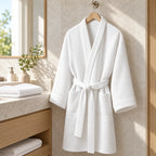 Albornoz blanco de tejido nido de abeja colgado en baño de hotel