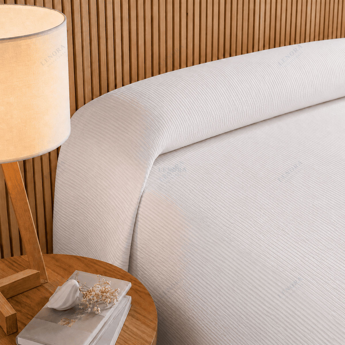 Cama de hotel vestida con colcha Otomán blanca junto a una lámpara