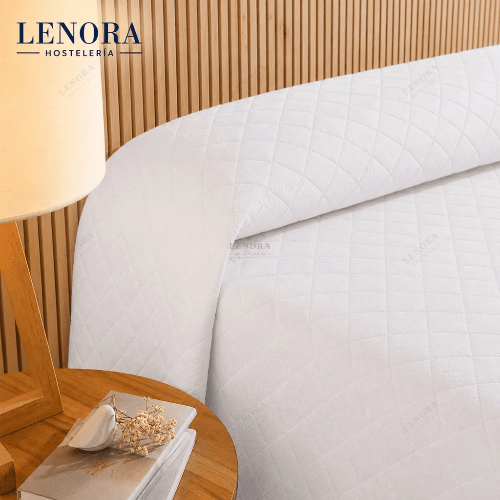 Cama de hotel vestida con colcha de rombos blanca