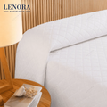 Cama de hotel vestida con colcha de rombos blanca