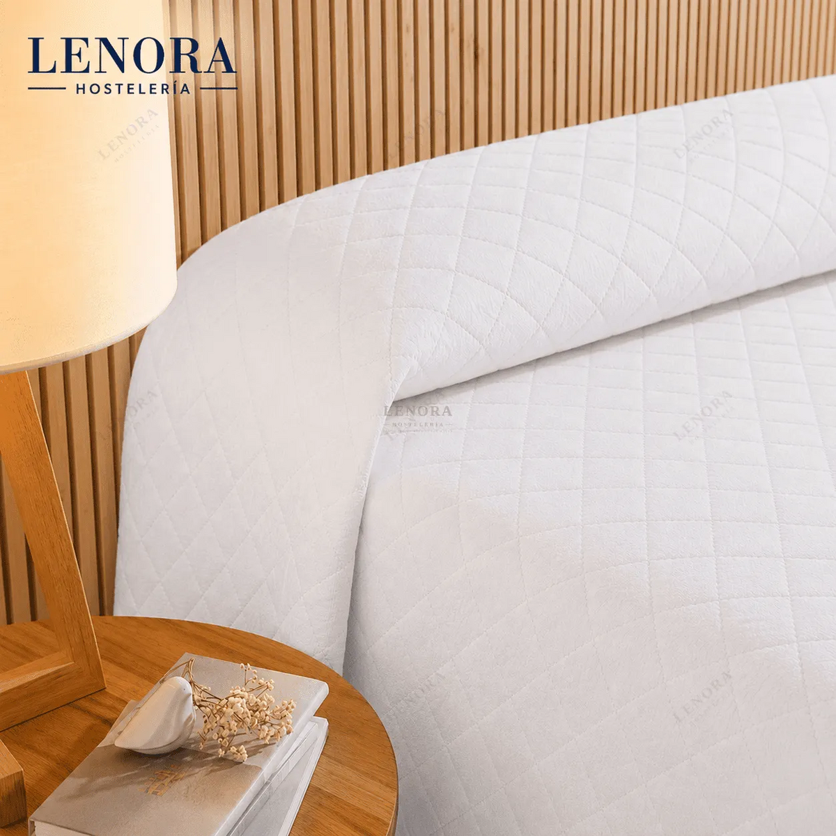 Cama de hotel vestida con colcha de rombos blanca