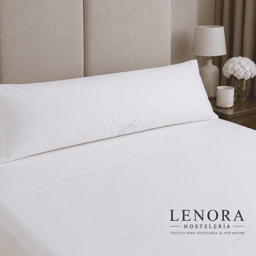 Cama de hotel con almohadas vestidas junto a una lámpara de noche