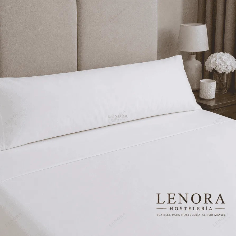 Cama de hotel con almohadas vestidas junto a una lámpara de noche