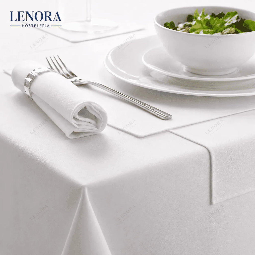 Mesa de restaurante vestida con mantel de satén blanco, servilleta y cubiertos