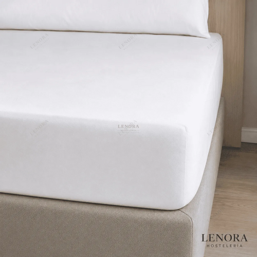 Sábana bajera ajustable blanca colocada sobre un colchón de hotel