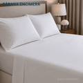 Cama de hotel vestida con sábana encimera blanca y almohadas