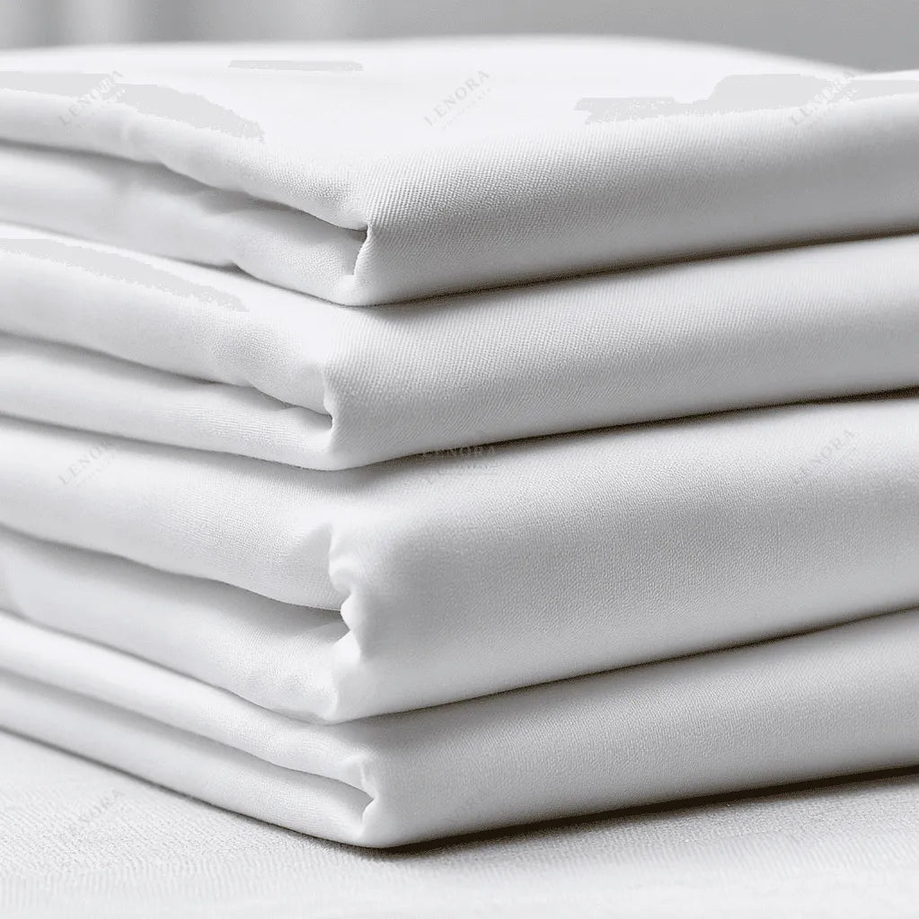 Sábanas encimeras blancas dobladas sobre fondo neutro