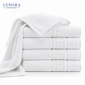 Toallas blancas con cenefa de greca apiladas y una desplegada